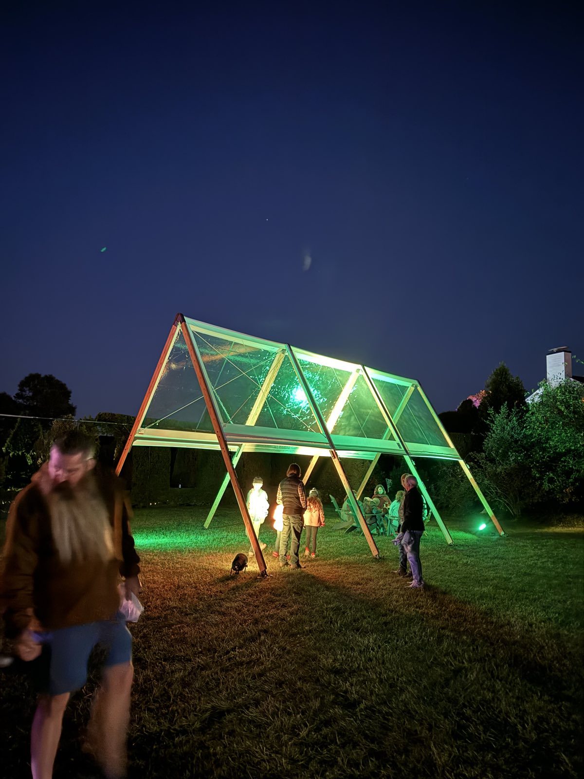 A-frame tents lit with colored lights at night