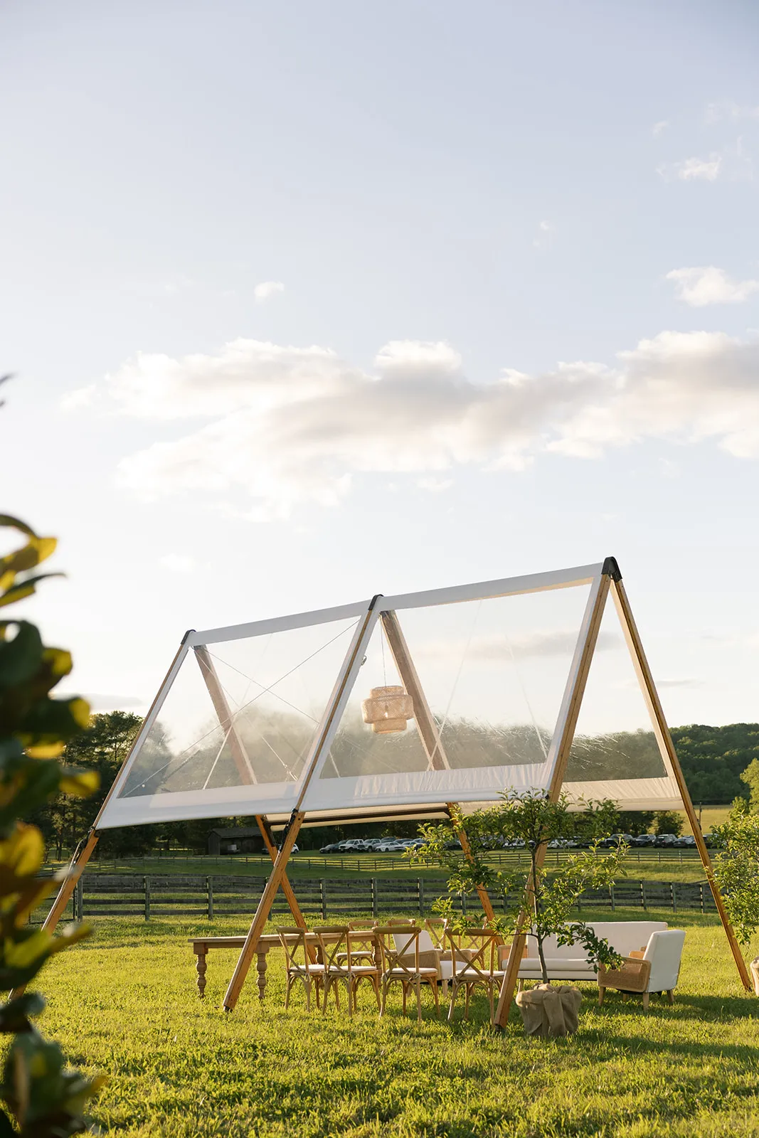Adena A-frame clear-top tent over a lounge seating area at golden hour