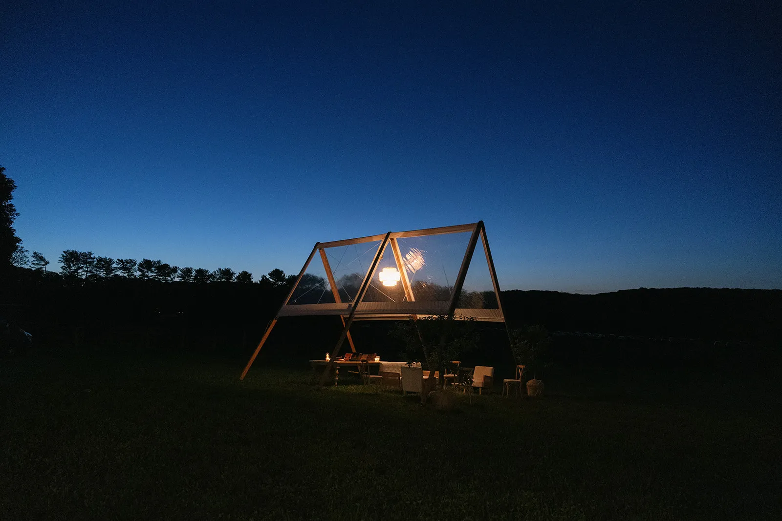 Adena A-frame tent glowing at night under a deep blue sky