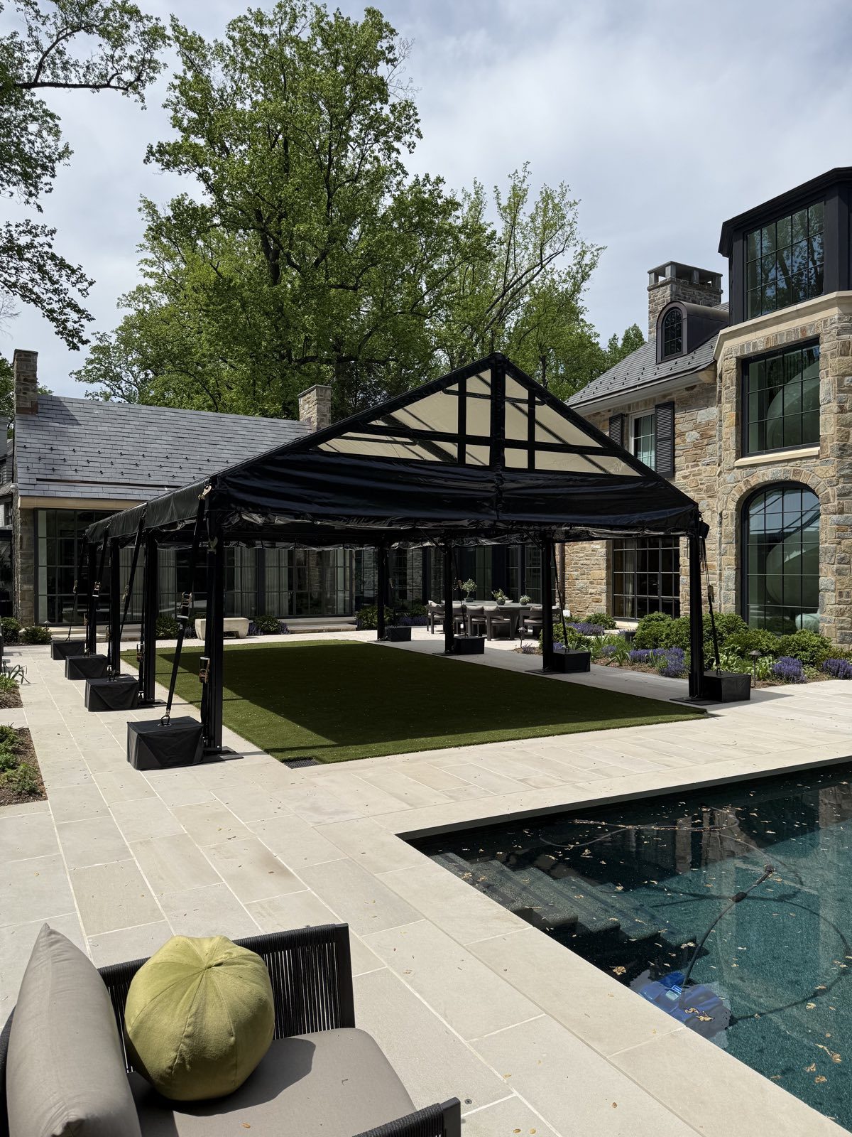 Black-frame pergola tents beside an estate pool