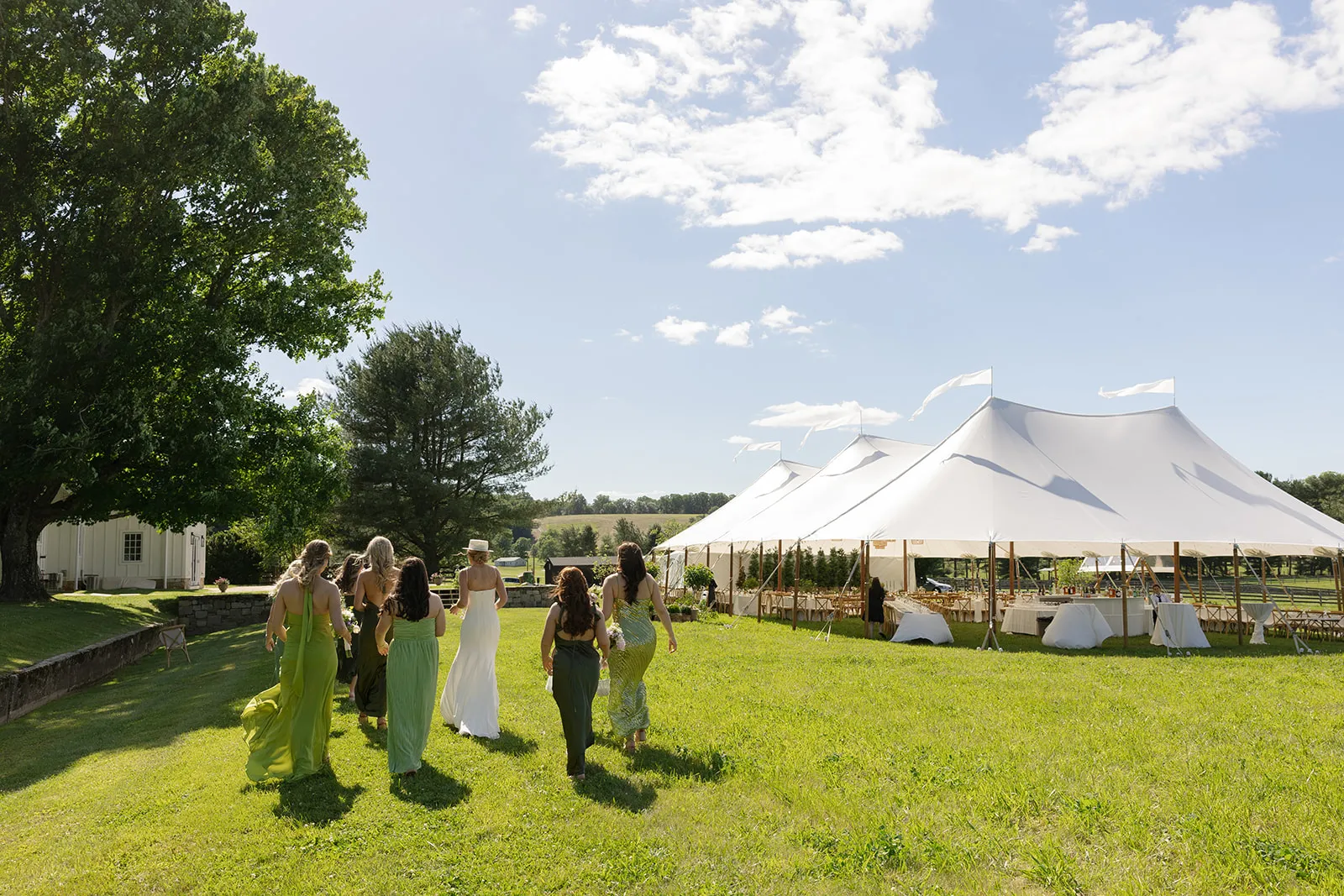 Bride and bridal party walking across the lawn toward sailcloth wedding tents at a Maryland farm reception