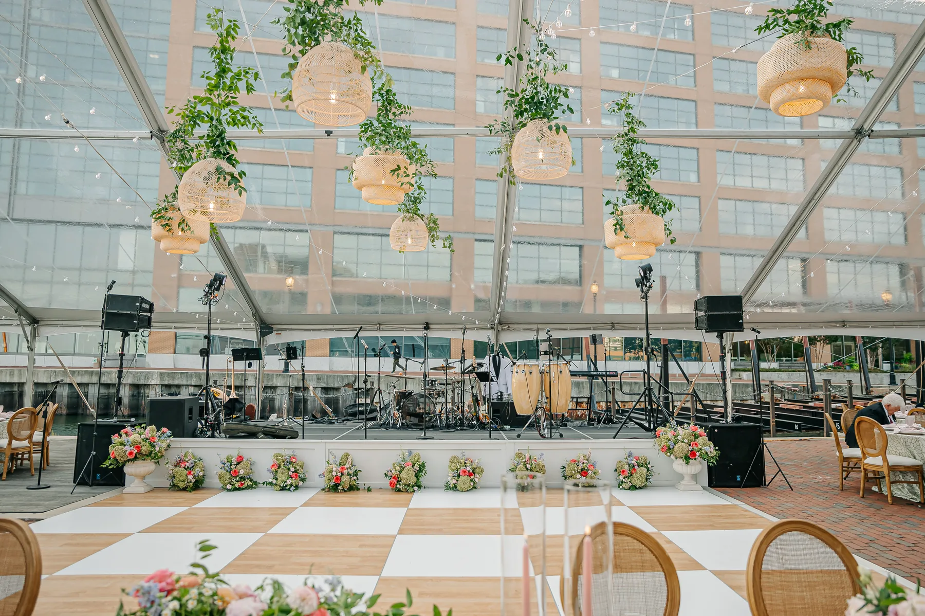 Checkerboard dance floor and stage inside a clear-top wedding tent