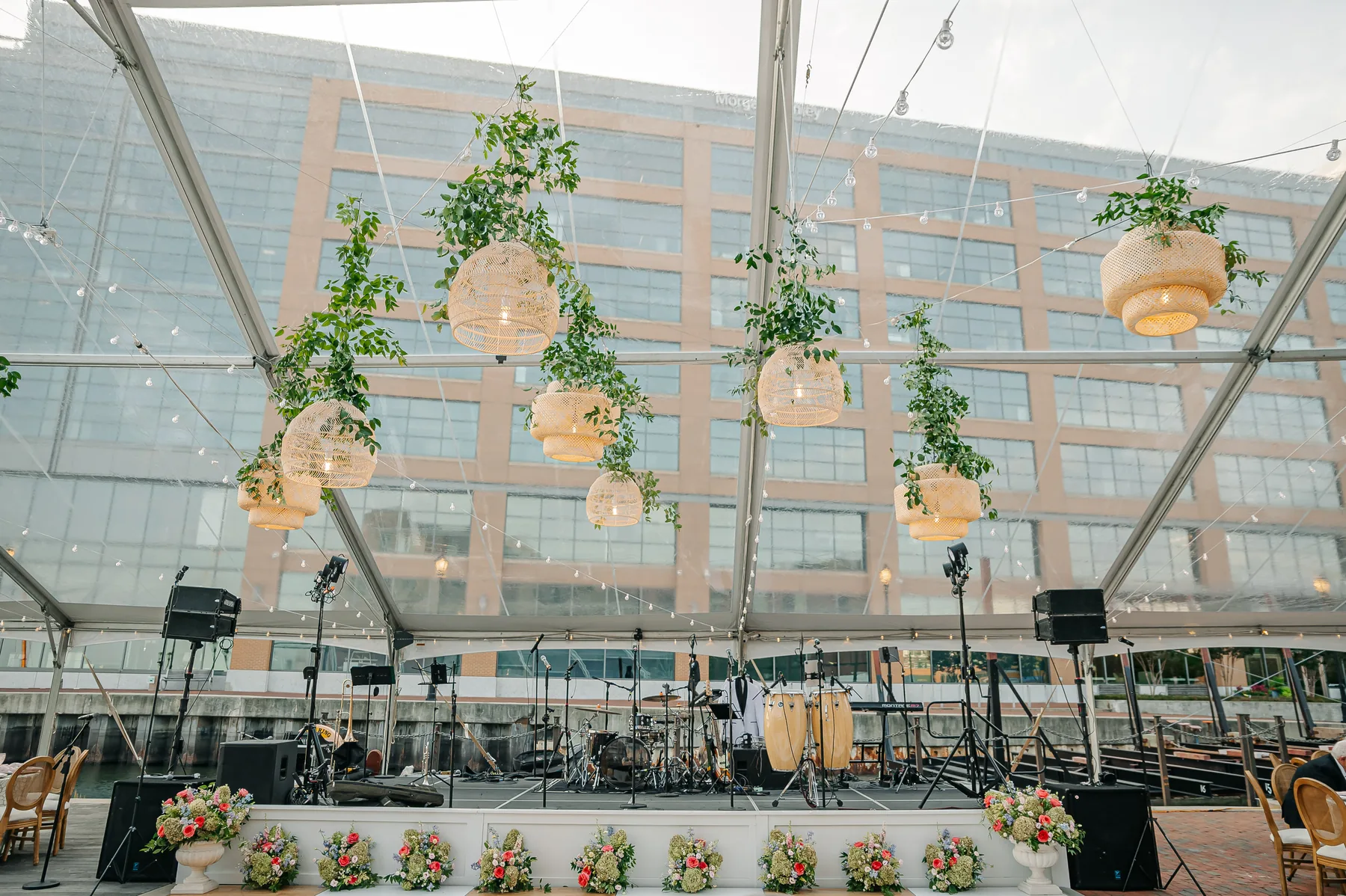 Stage and hanging greenery inside a clear-top event tent