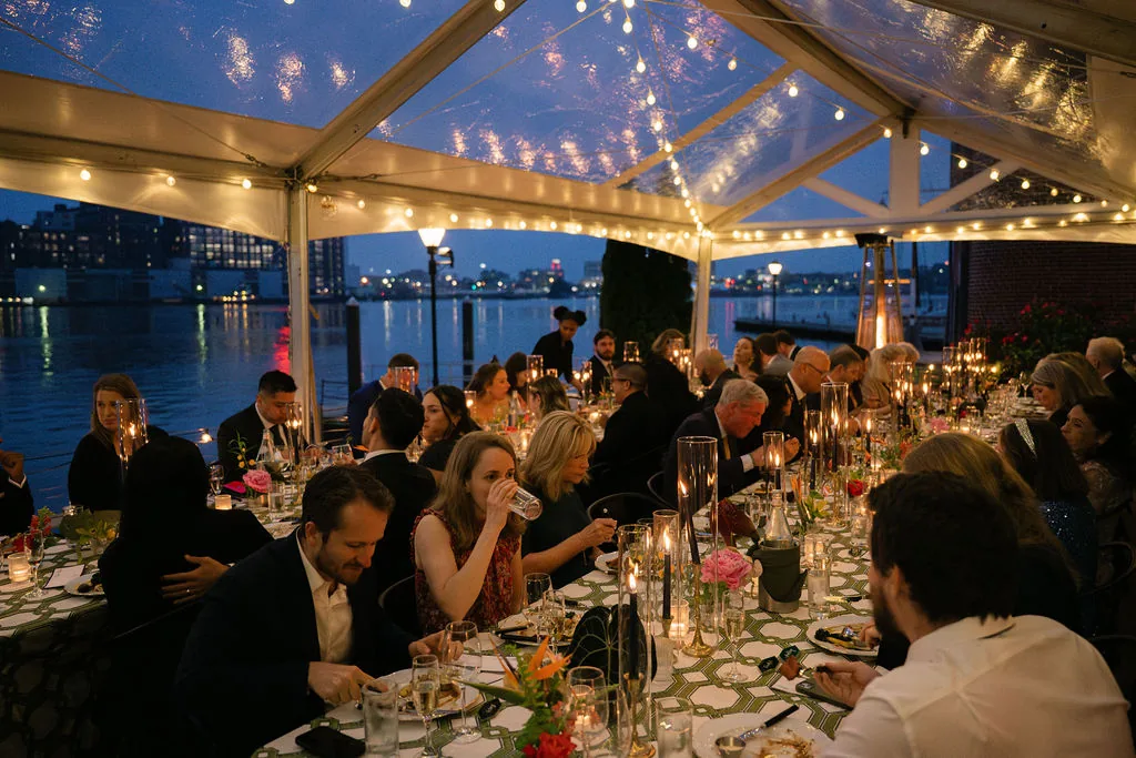 Dinner beneath a clear-top waterfront wedding tent at night
