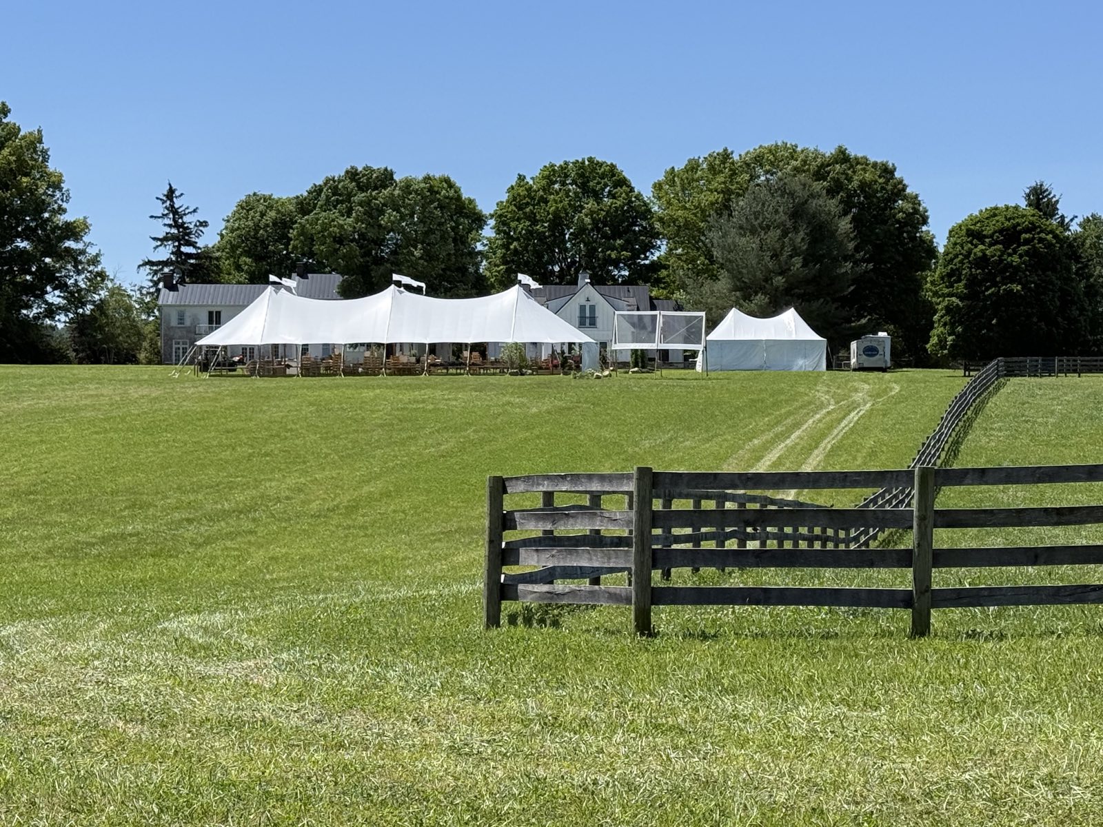 Sailcloth tents on an estate behind a board fence