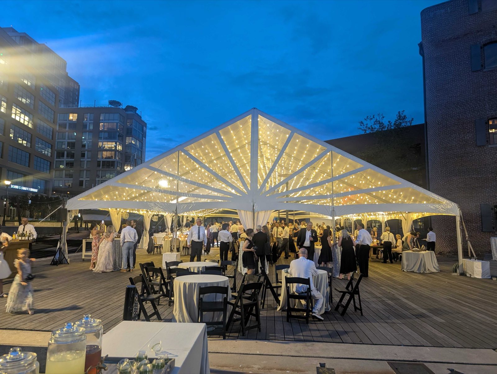 Evening reception under a lit frame tent on a deck