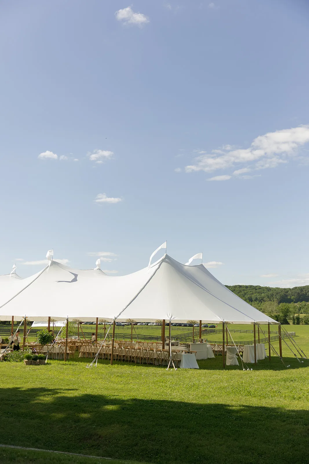 Sailcloth tent peaks with pennant flags above a farm wedding reception