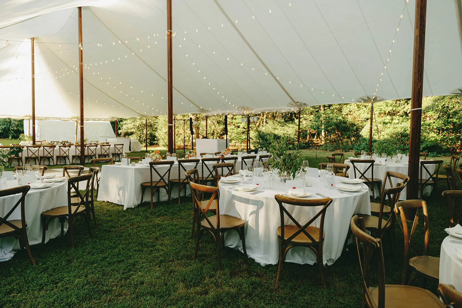 Round and long reception tables inside a sailcloth tent