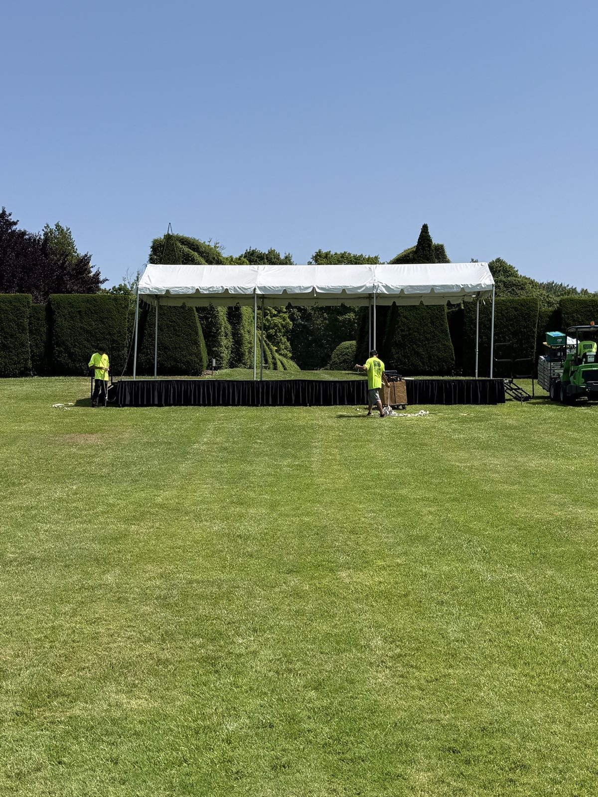 Crew building a stage along a hedge line