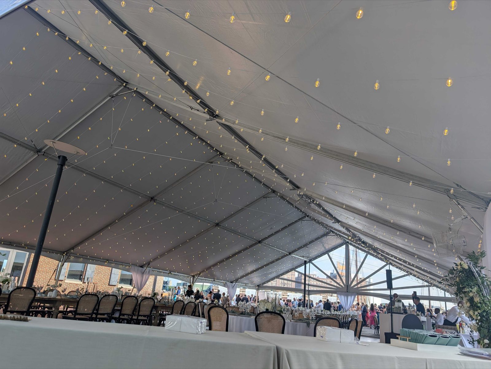 Twinkle lights over long tables inside a tent
