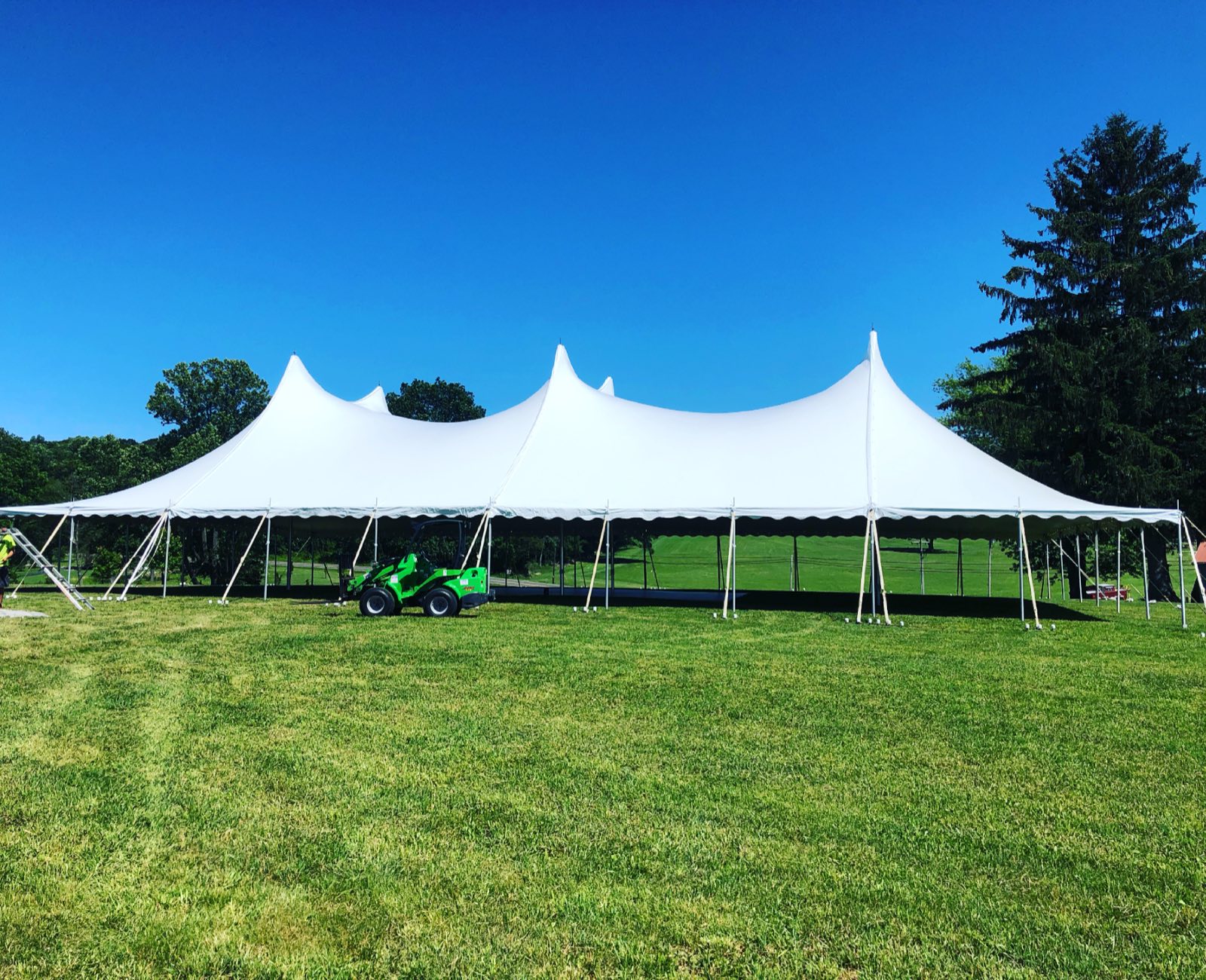 Two sailcloth tents side by side on an estate lawn