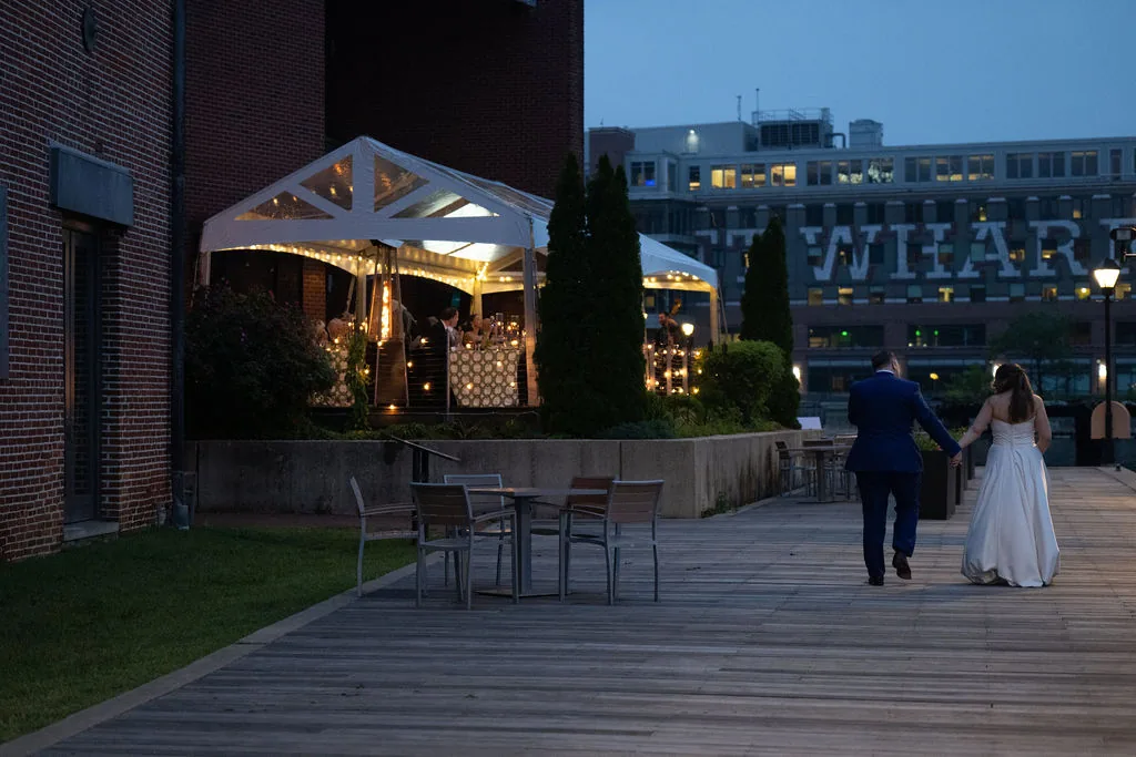 Couple walking toward a waterfront wedding reception tent