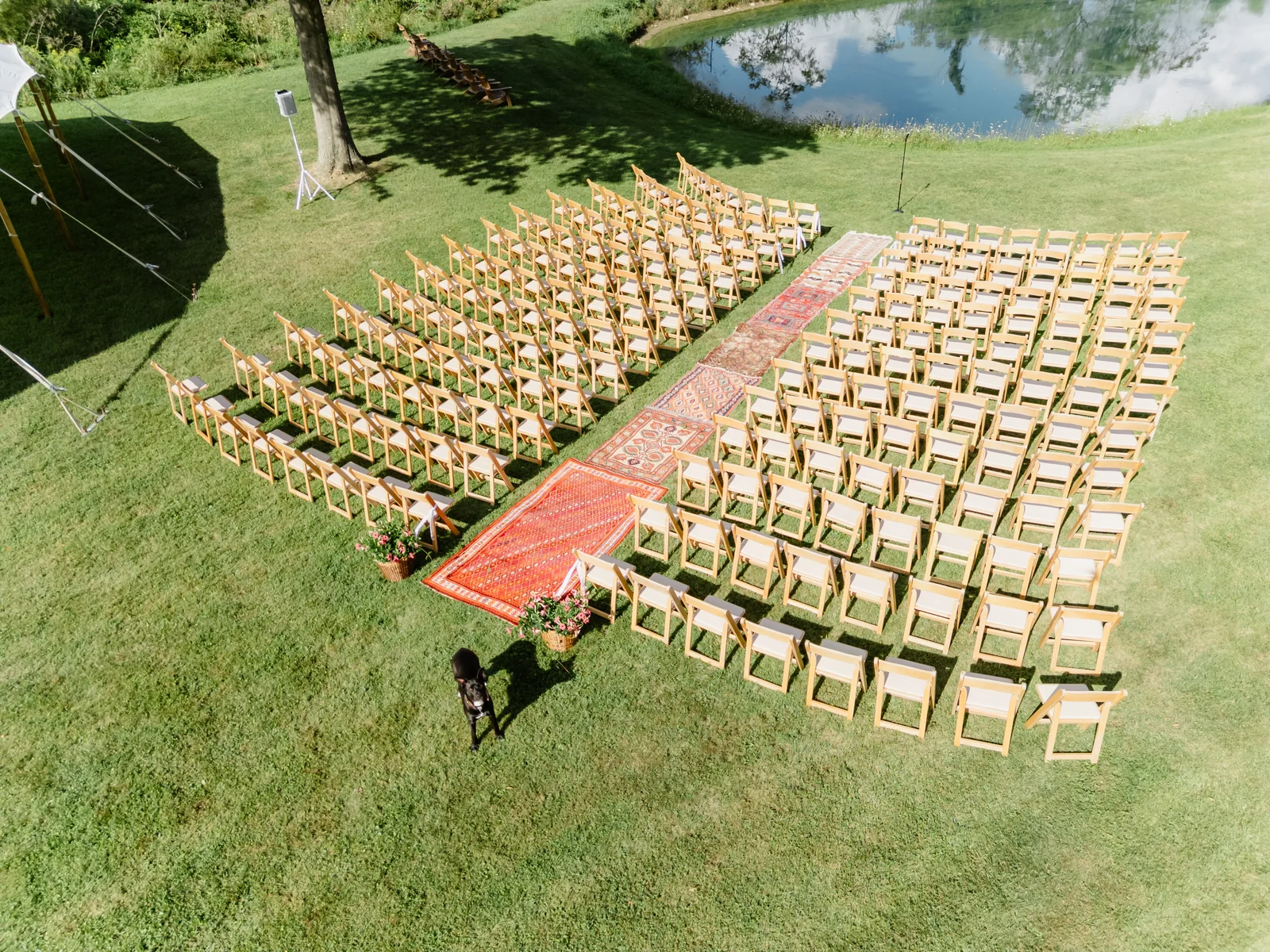 Outdoor wedding ceremony chairs arranged around a brick aisle beside a pond