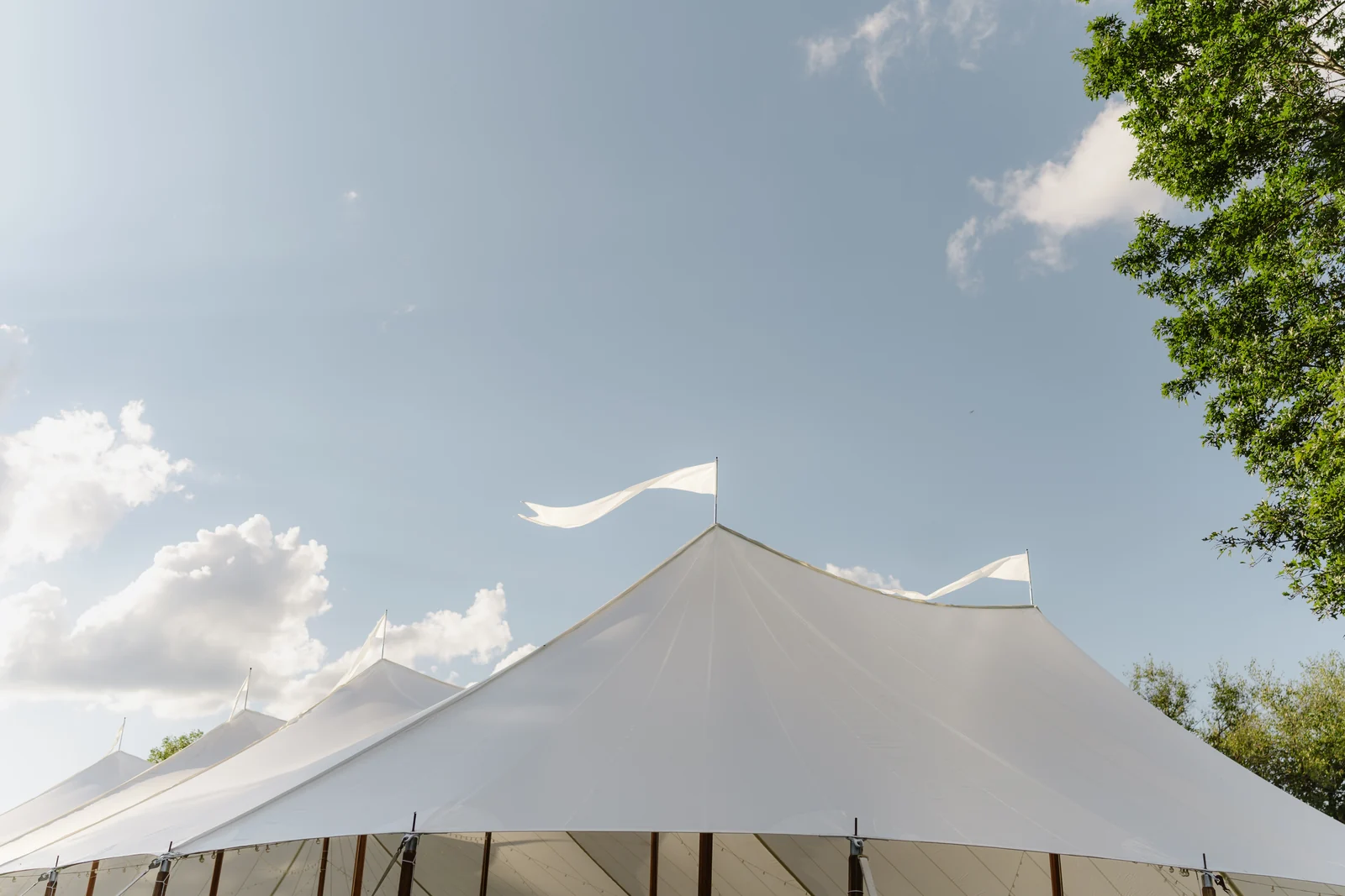 White sailcloth tent peaks and pennant flags against a blue sky